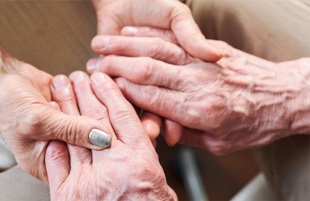 Elderly couple holding hands, signifying the importance of caregiver support and resources