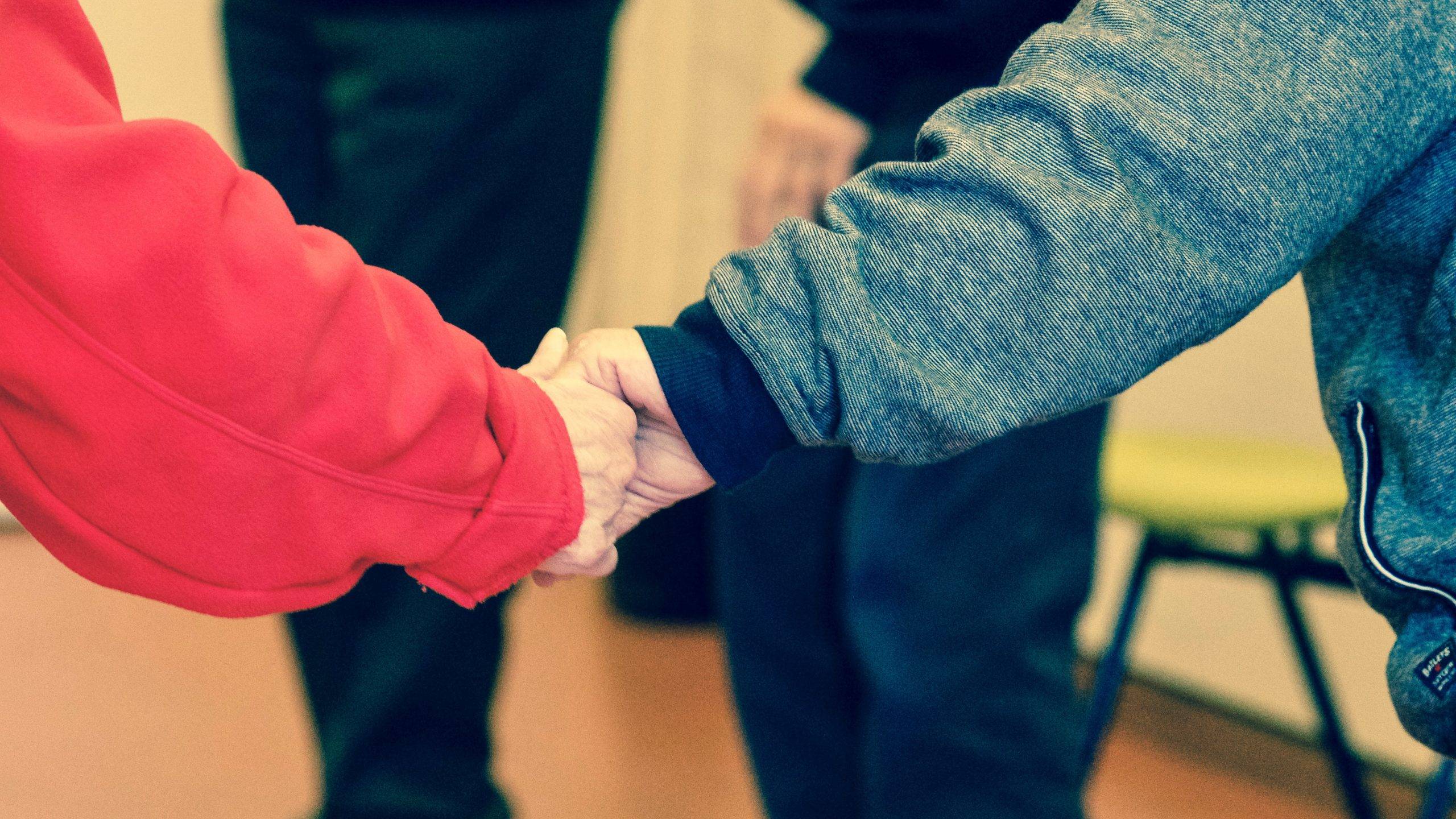 Two people holding hands, signifying community and compassion