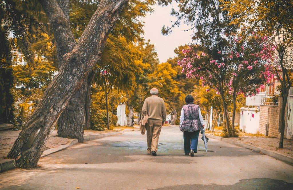 elderly couple on a walk outside on a tree lined street