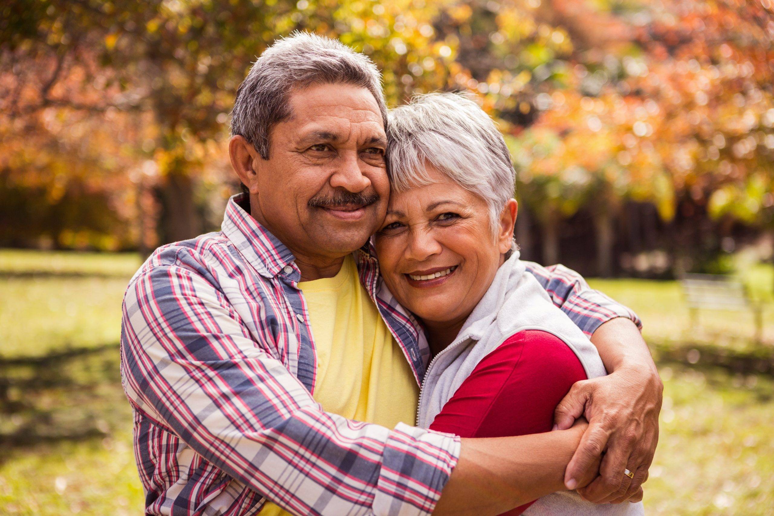 elderly couple outside, hugging and smiling