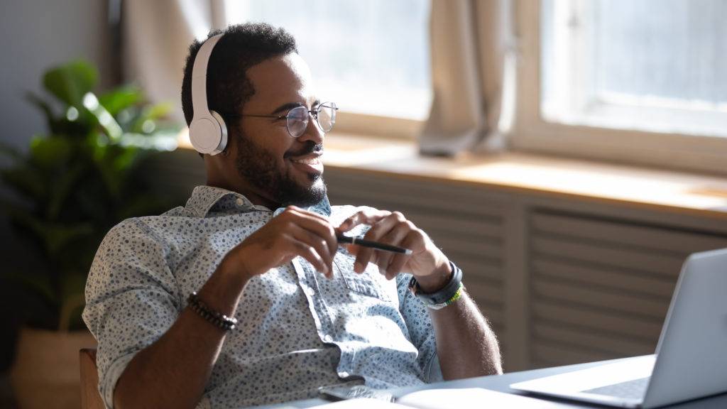 happy man at laptop listening to music on headphones