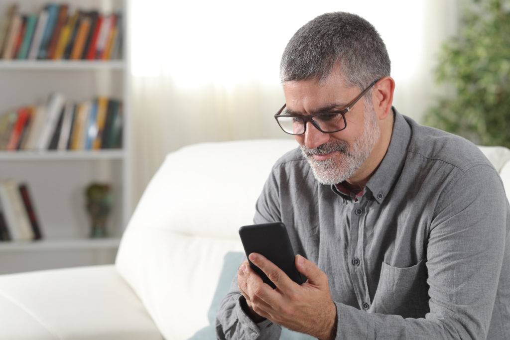 Adult man sitting on couch using a smart phone