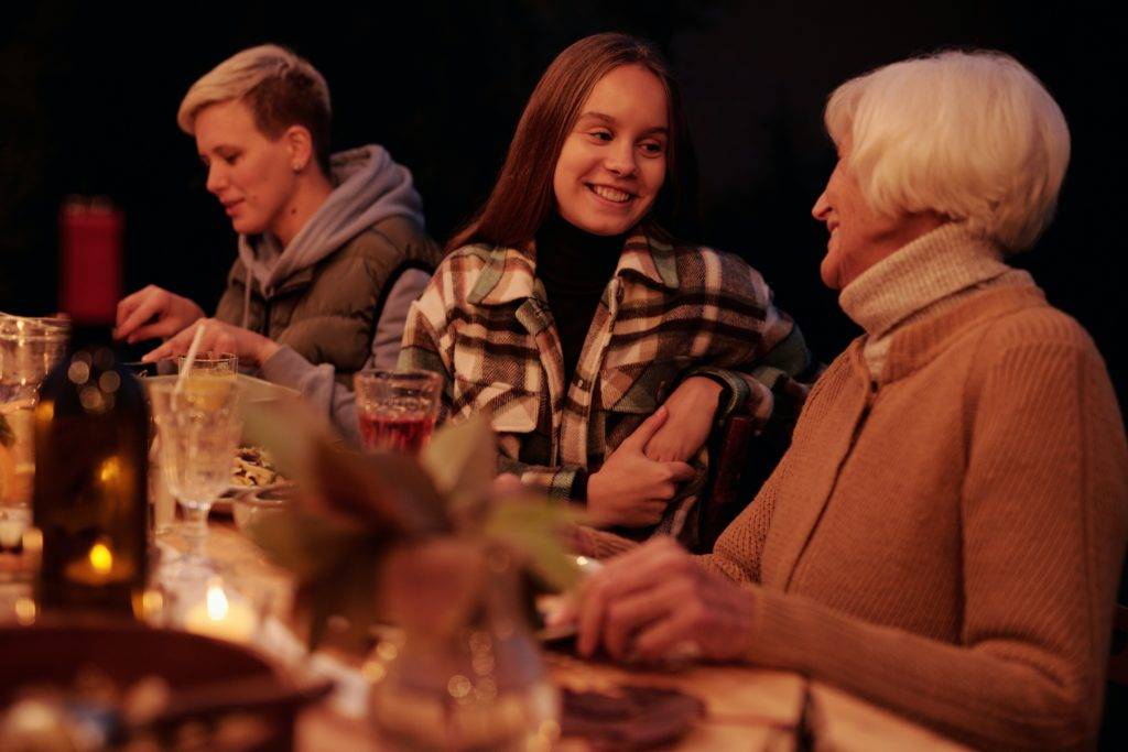 young woman talks to grandmother at outdoor dining table