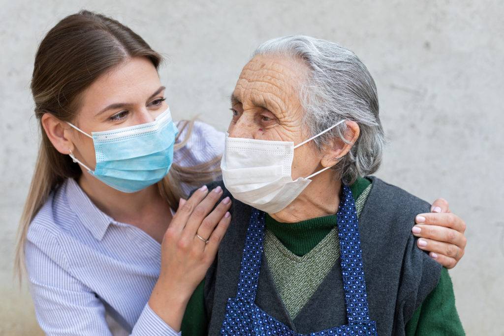 young woman with elderly woman, both wearing masks