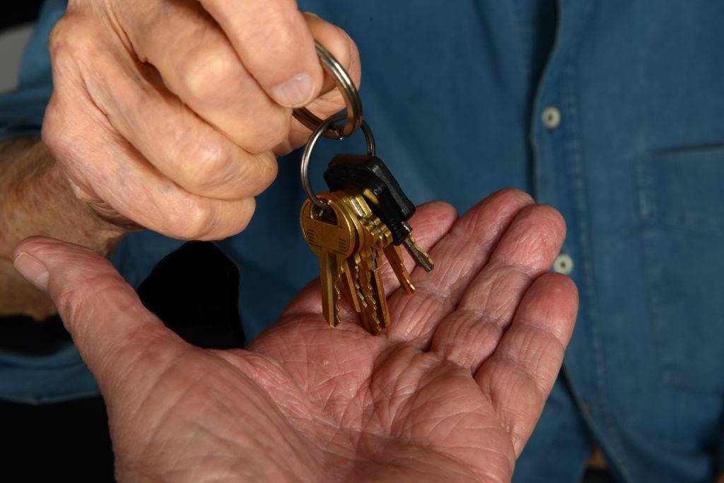 Elder man handing car keys to someone