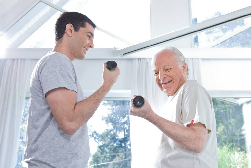 Young man and elderly man lifting small handheld weights