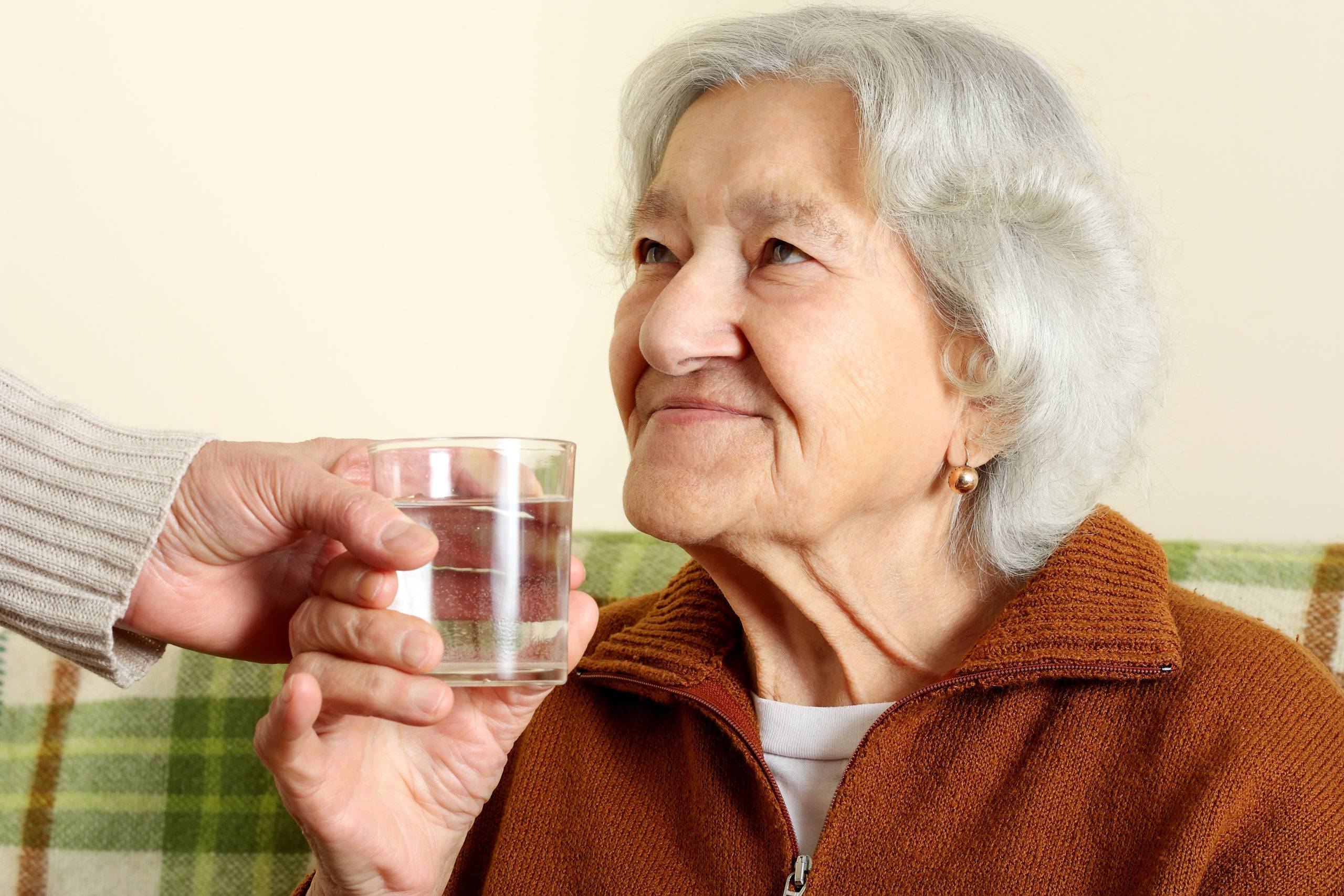 elderly woman holding glass of water