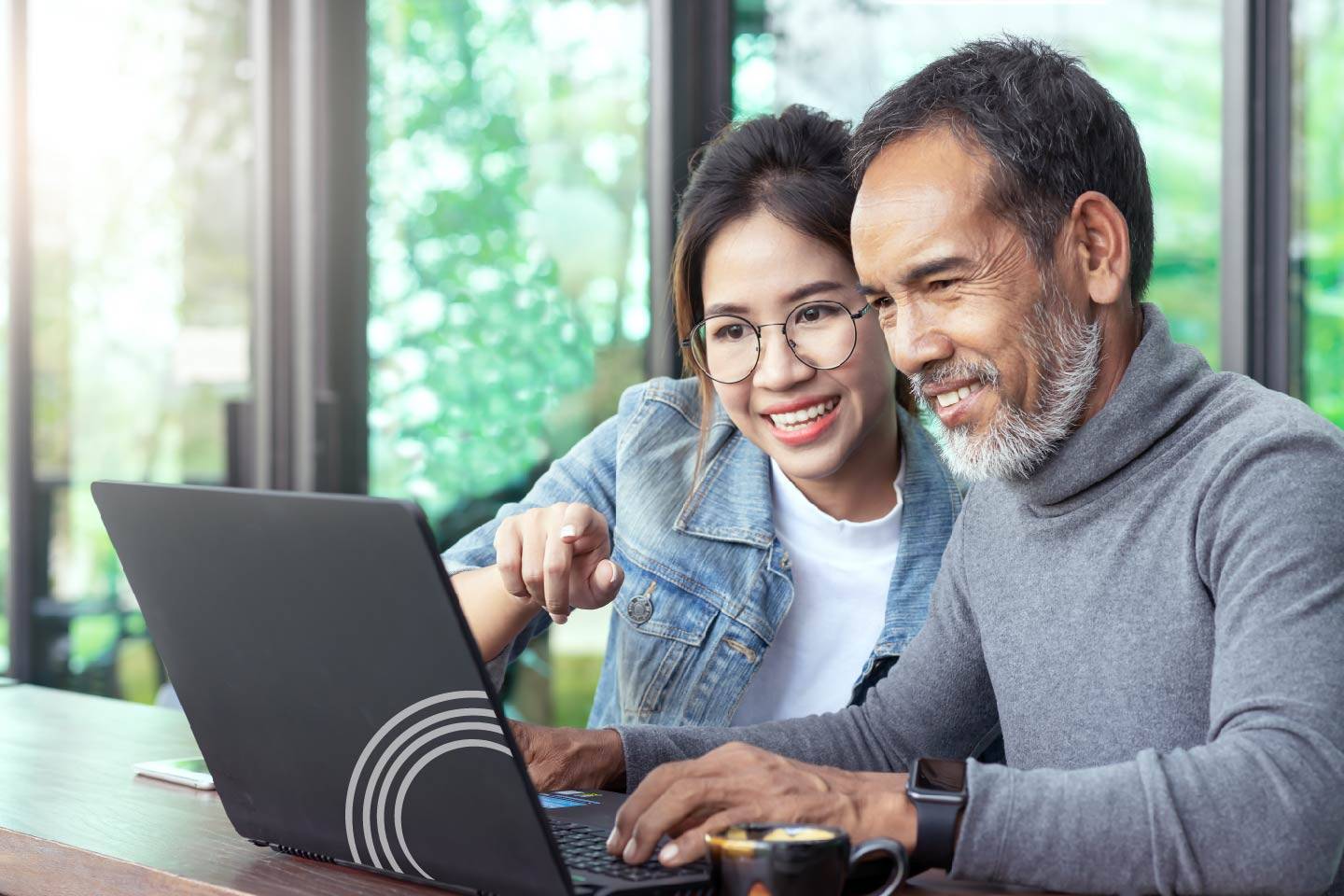 Young woman and elderly man using laptop