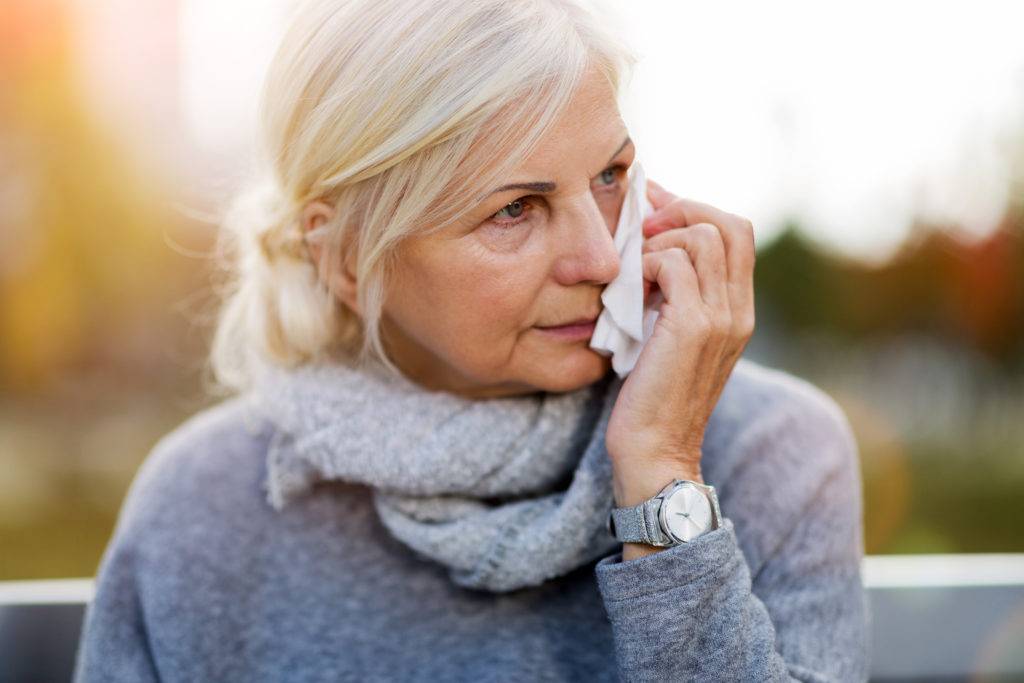 Elderly woman crying, holding tissues