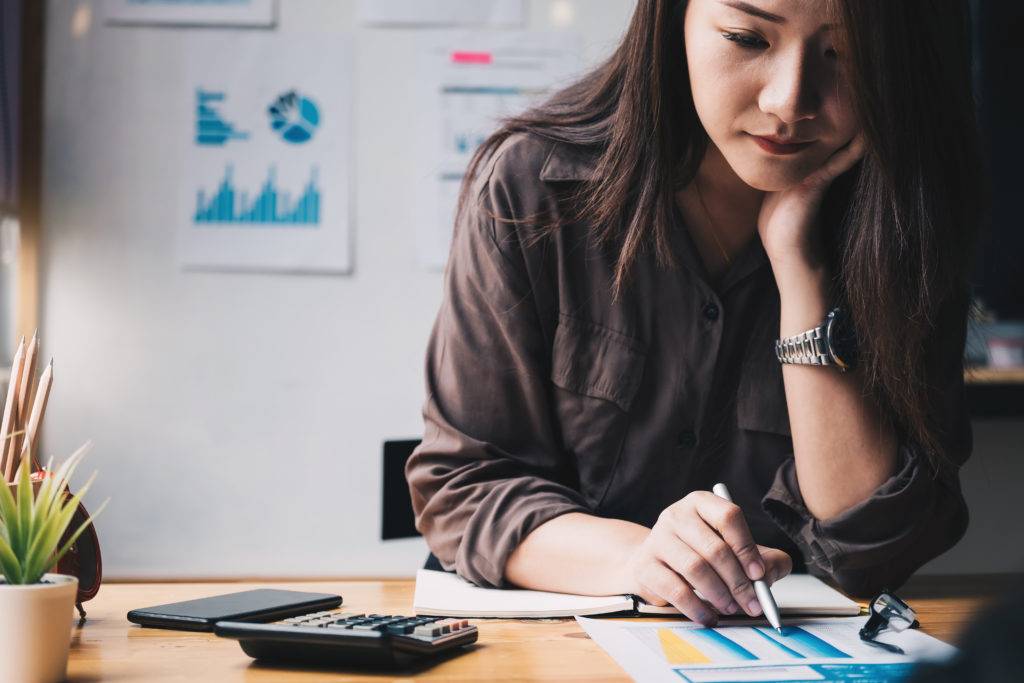 Young woman doing business at her desk with calculator and paperwork