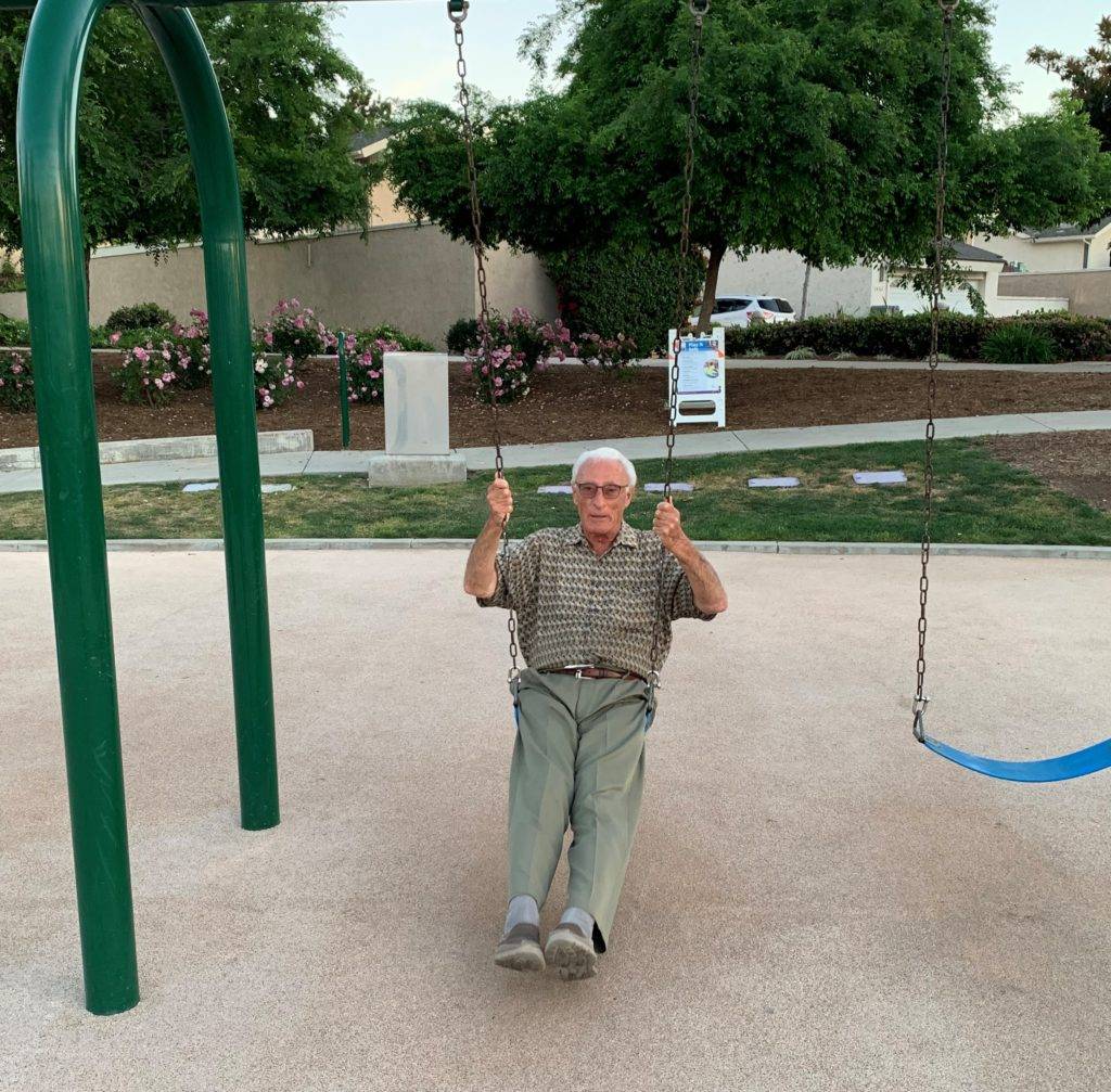 Elderly man on swing set outside
