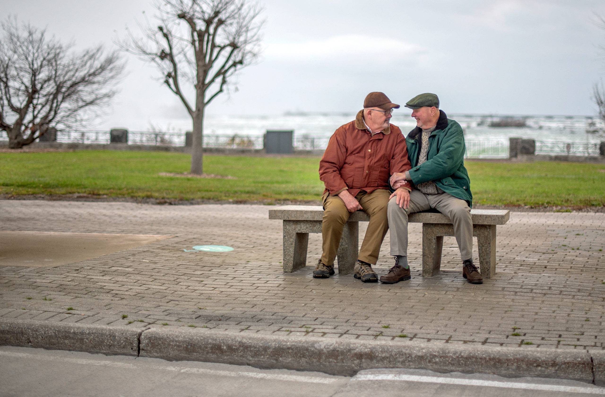 Two elderly men sitting on bench outdoors