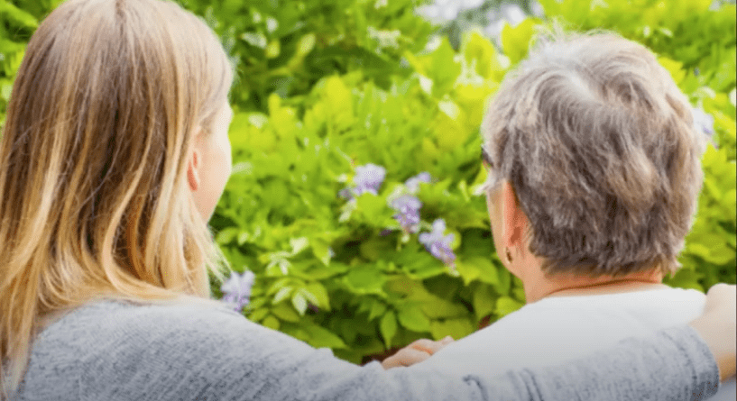 Elderly person and adult daughter looking at garden