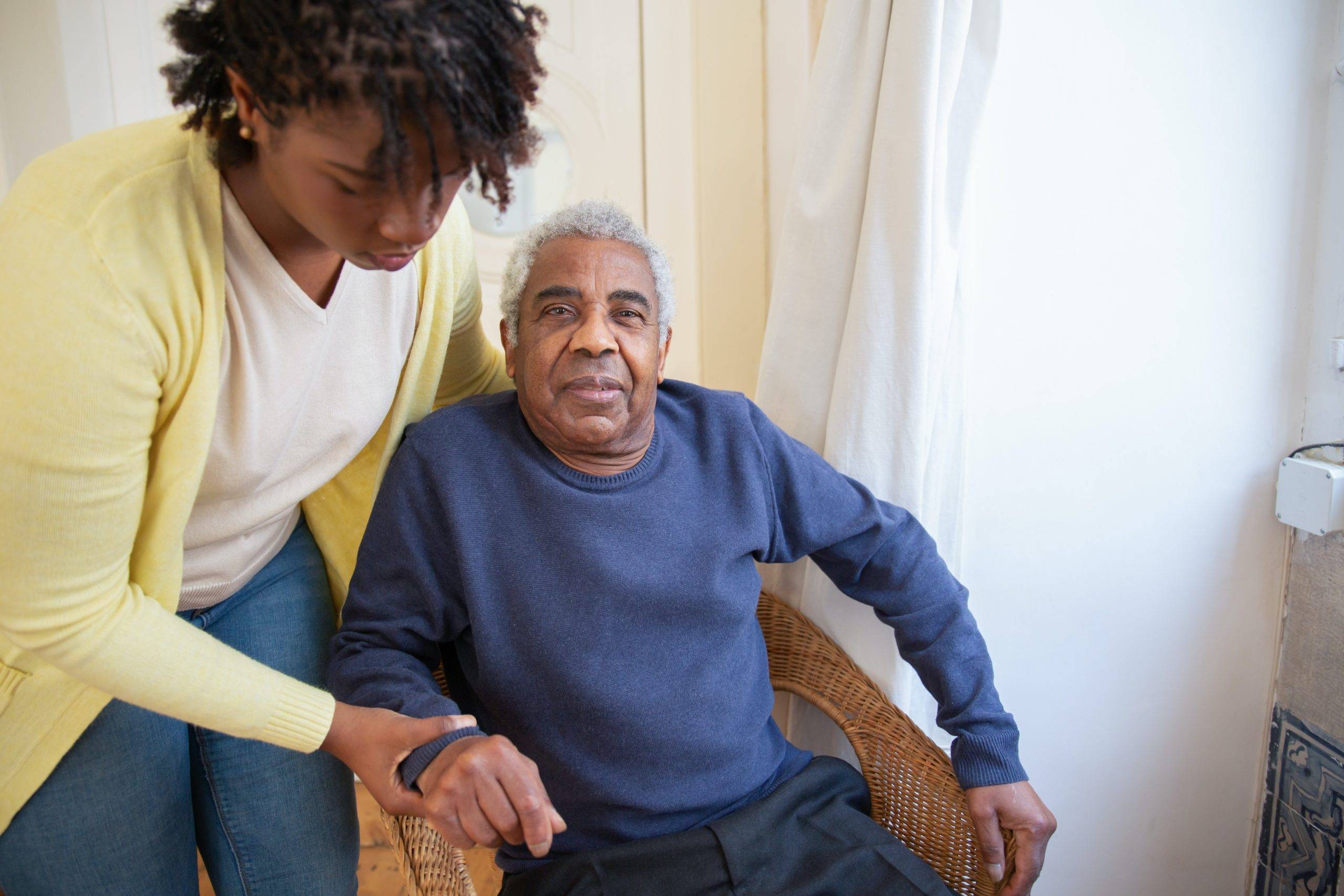 Elderly man seated, assisted by adult daughter