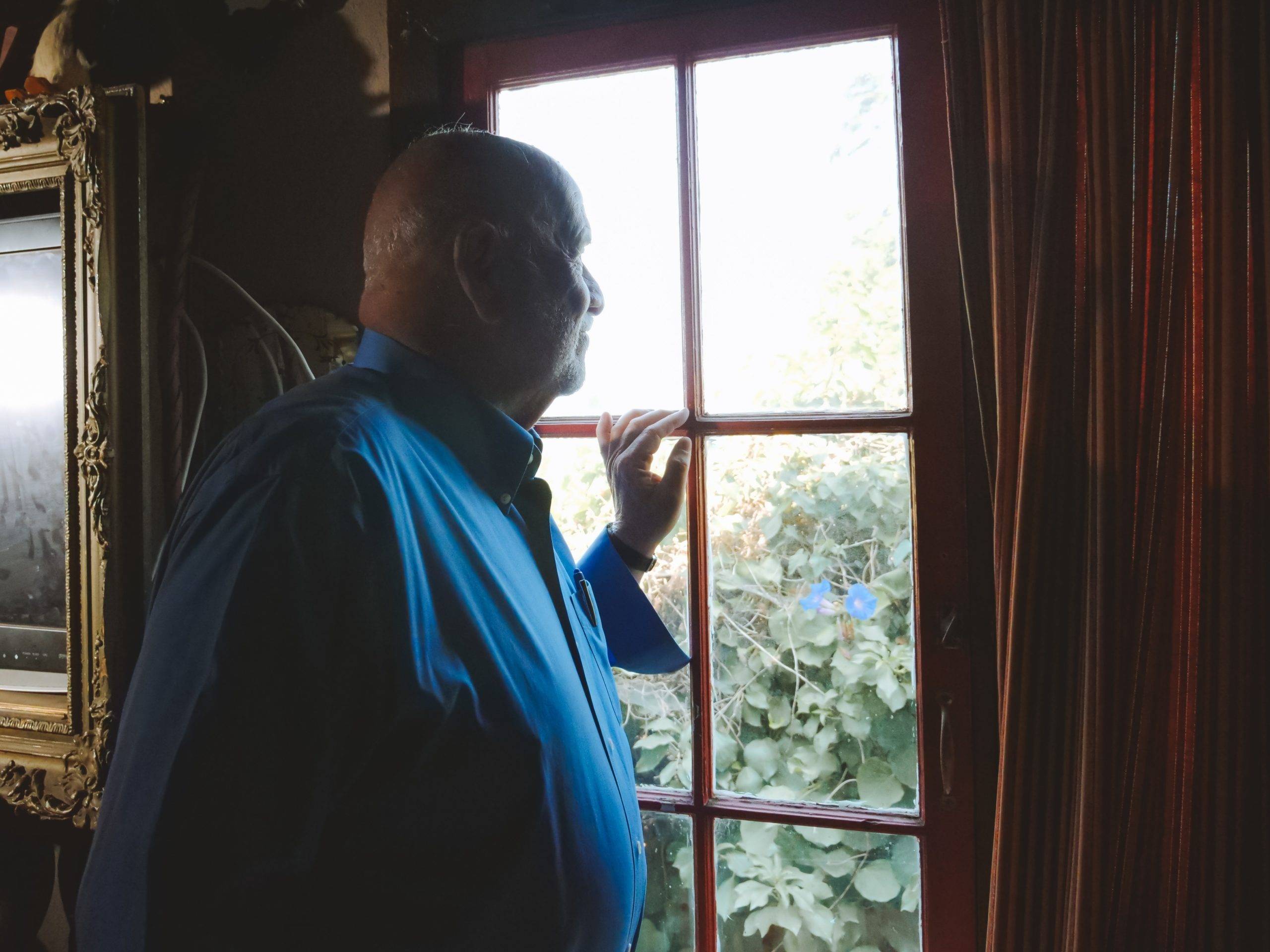 Elderly man looks out window