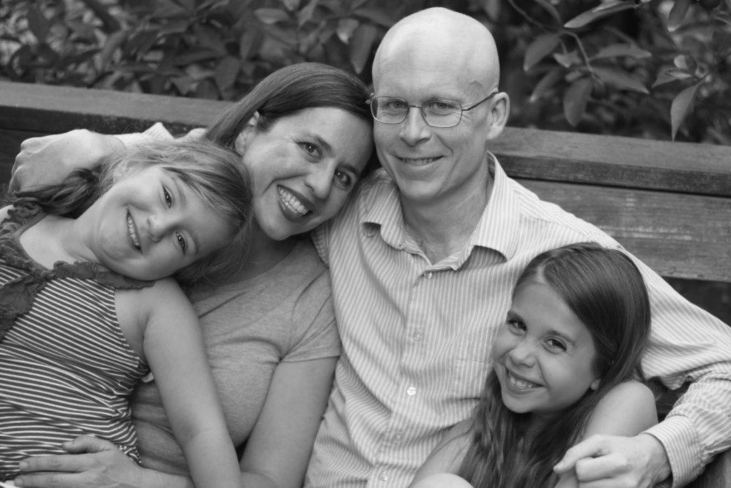 Happy family seated outside on bench and smiling