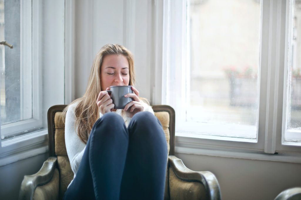 Young woman sits with coffee cup, smiling