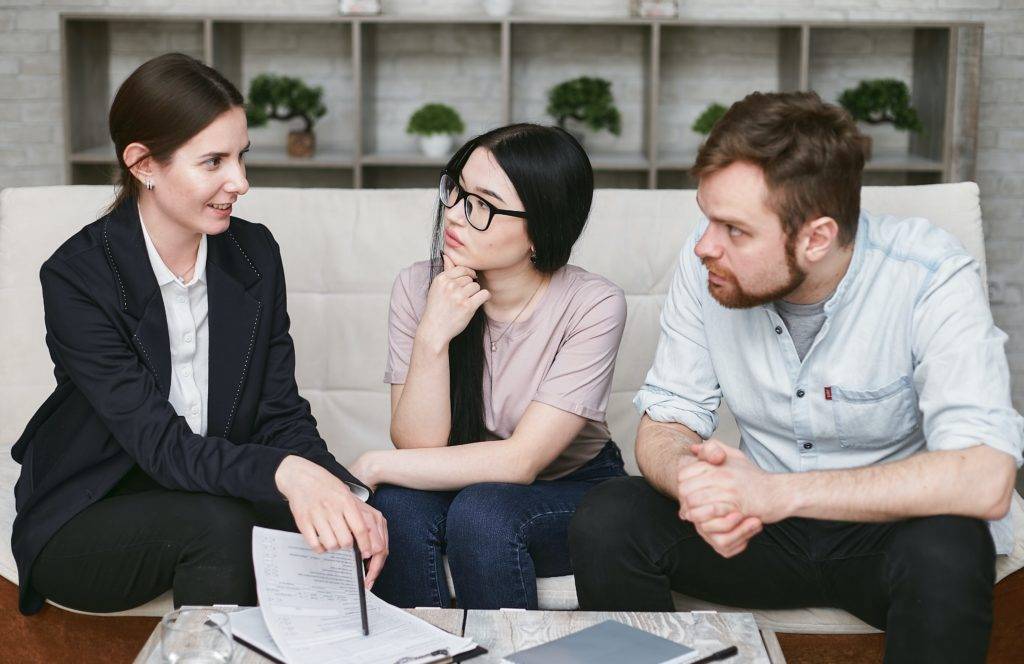 Young couple sits on couch, meeting with consultant