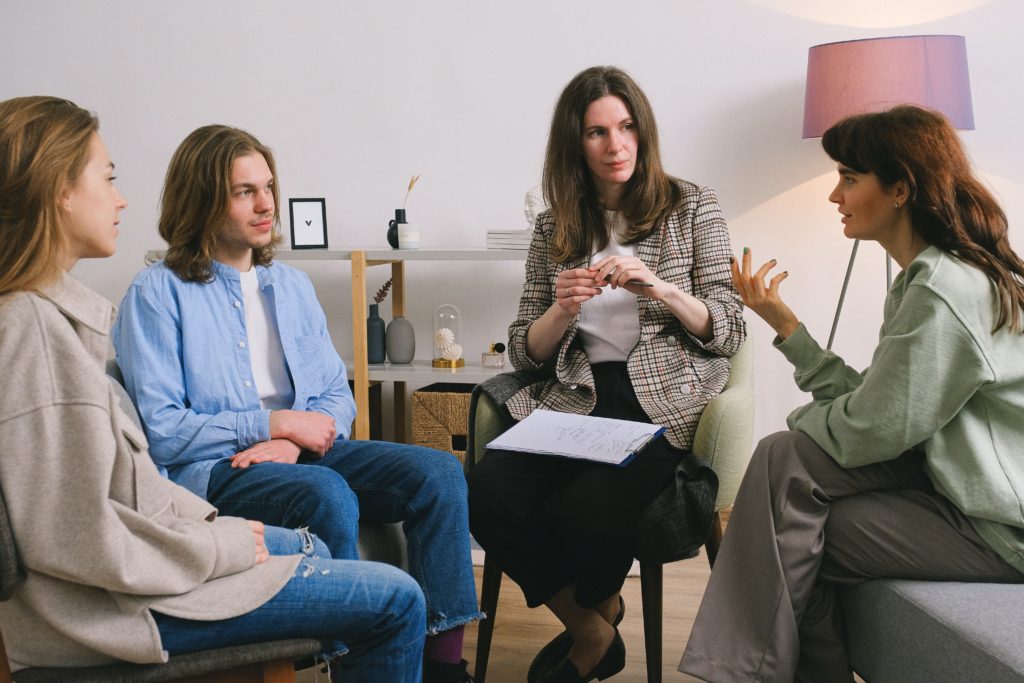 group of four people sitting and talking in support group