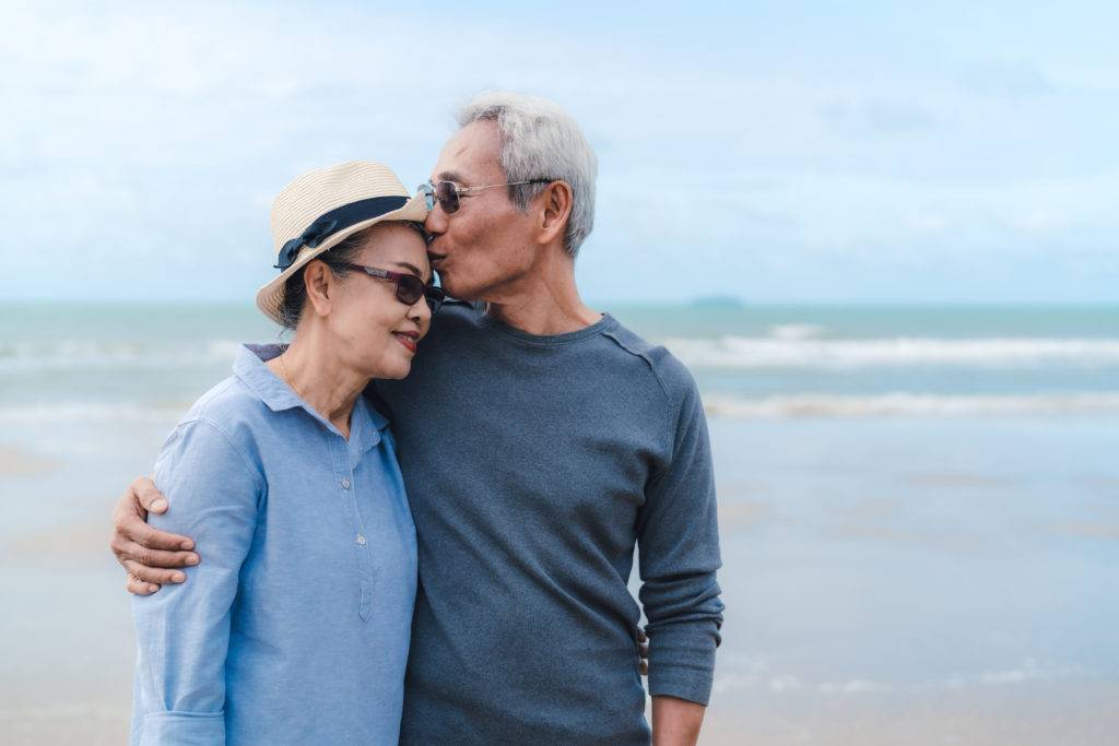 Elderly couple on beach, man kissing woman on forehead