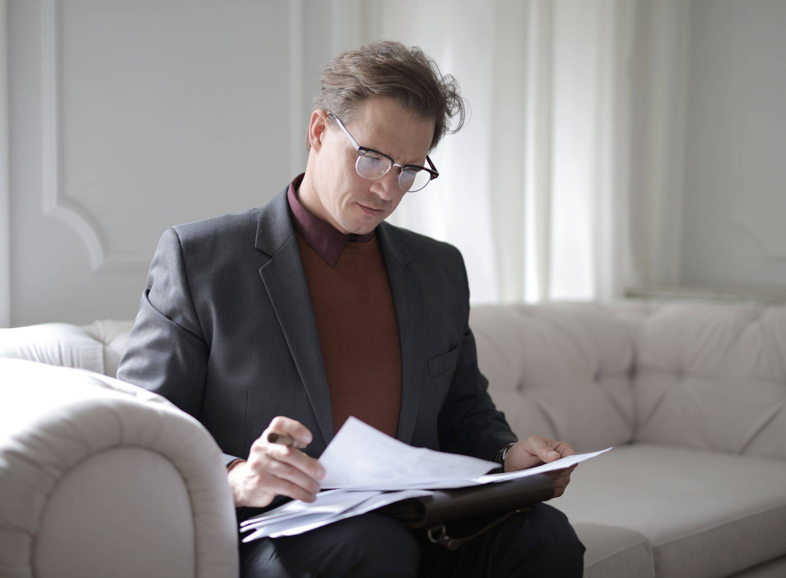 Adult man sitting on couch reviewing documents