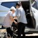 Elderly woman gets out of wheelchair and into car with support of adult daughter